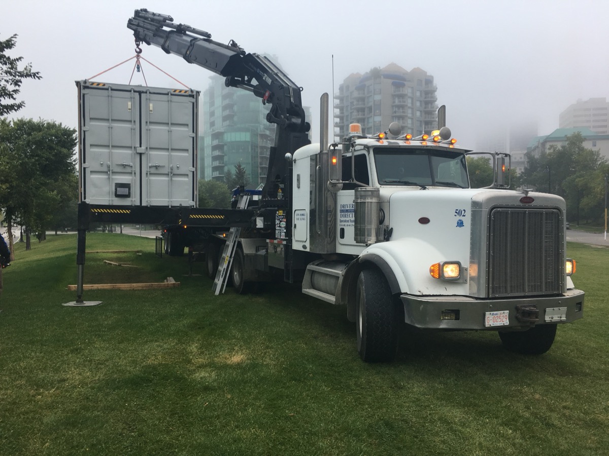 Crane truck delivering the shipping container to the Bow River pathway