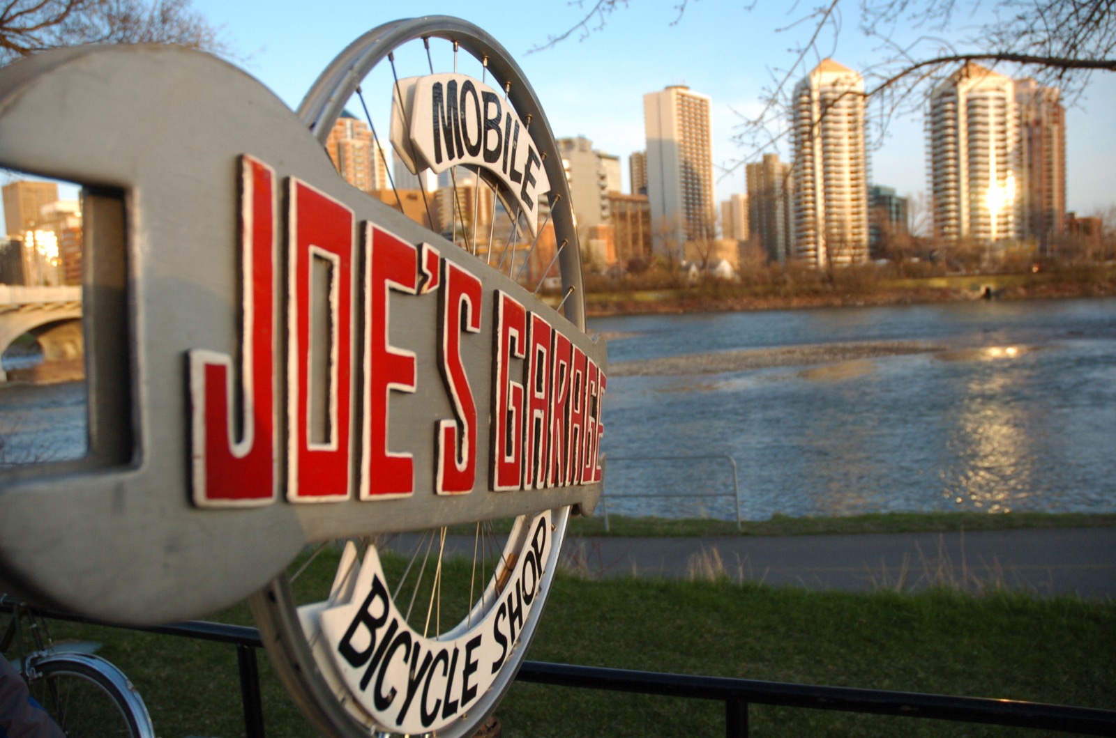 Joe's Garage sign with the Bow River and Calgary skyline at golden hour