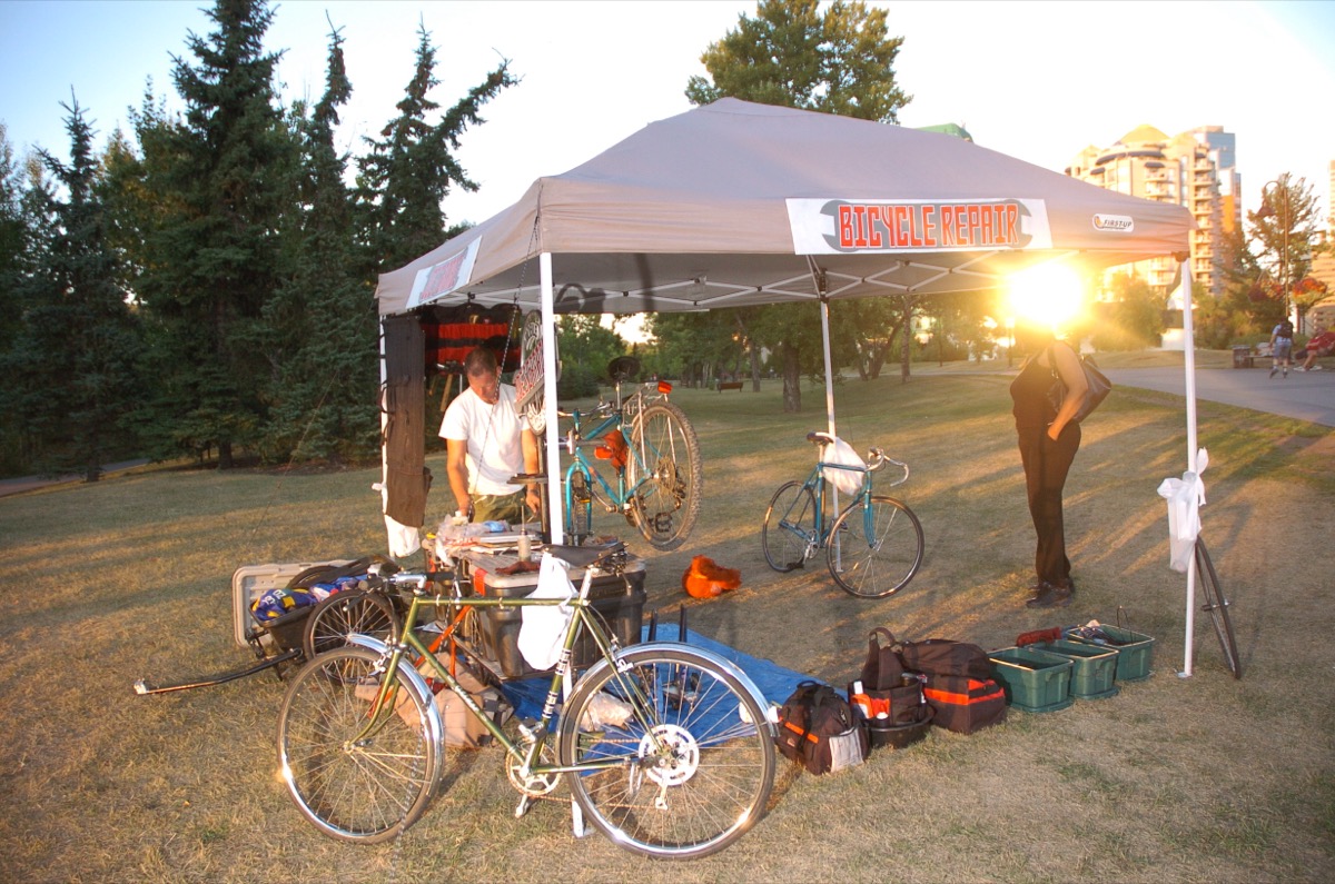 Bicycle repairs under the tent at sunset on the Bow River pathway